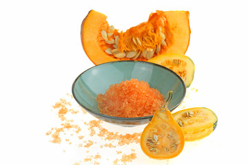 Pumpkin bath salt. Cosmetics for the body with pumpkin extract.  salt with pumpkin extract in blue cup and pumpkin in a cut on a white background