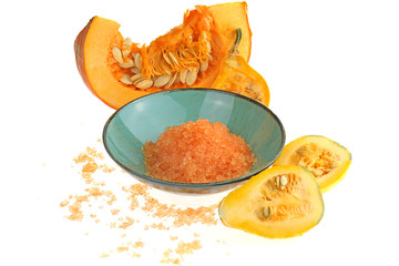 Pumpkin bath salt. Cosmetics for the body with pumpkin extract. Sea salt with pumpkin extract in blue cup and pumpkin in a cut on a white background
