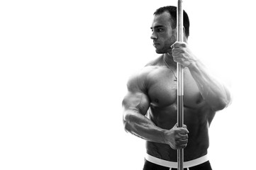 Fototapeta na wymiar Handsome male fitness model posing shirtless, holding barbell in hands. Black and white image, place for text. High resolution.