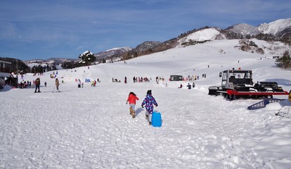 スキー場でそり遊びをする子供たち