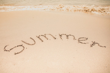 Summer word is written on the beach sand