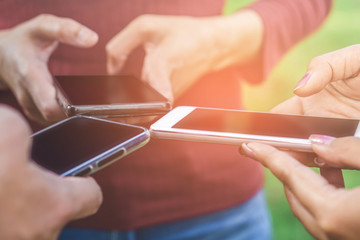 teenager friend group having fun at park using smart phone connecting to social media together, people lifestyle with technology concept background