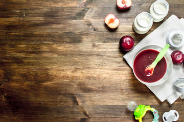 Baby food. Puree from fresh plums with baby milk in a bottle.