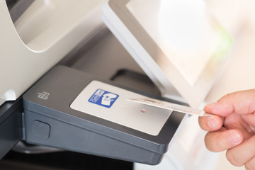 A businessman hand hold card for access Photocopier. Modern induction technology identify personal information. Security system concept