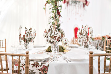 Interior of a wedding tent decoration ready for guests. Served round banquet table outdoor in marquee decorated flowers and silk. Catering concept