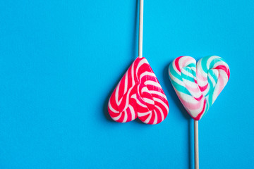 Close up and top view of colorful heart shaped striped lollipops isolated on blue background with...