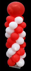 High vertical installation of red and white balloons on a granite stand.