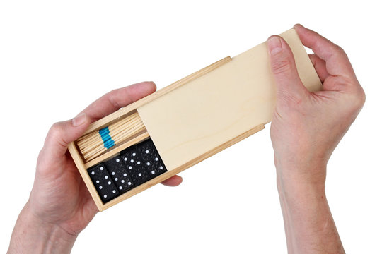 The old man grandpa opens a wooden box with board games - dominoes and mikado