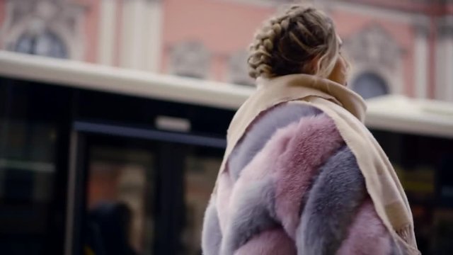 a young woman in a stylish and fashionable fur coat strolls through the winter city, the lady enjoys a walk