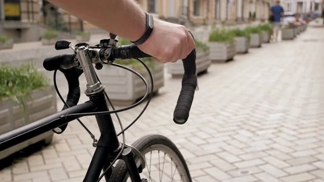 Closeup slow motion video of male hand holding vintage bicycle handle while walking on street