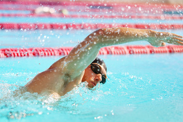 Triathlon fit athlete training in swimming pool lane at outdoor stadium. Swimmer man swimming in...