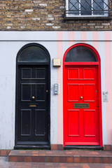 Black door next to a red door in the front facade of a Victorian British English house