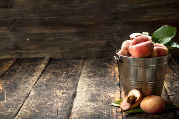 Fresh peaches in a bucket with leaves. © Artem Shadrin
