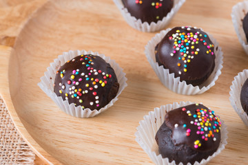 Colorful Chocolate Sprinkles on Tasty Round Chocolate Coated Cakes