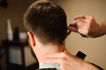 Master cuts hair and beard of men in the barbershop