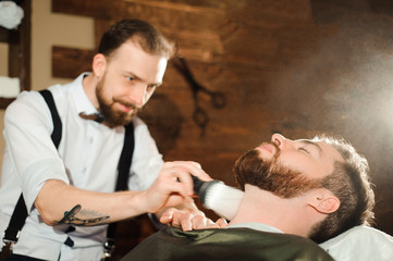 Master cuts hair and beard of men in the barbershop