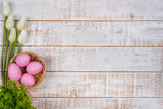 Colorful easter eggs and tulips over white wooden table
