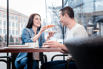 Taste it. Shy male person expressing positivity while looking at his girlfriend and sitting in semi position