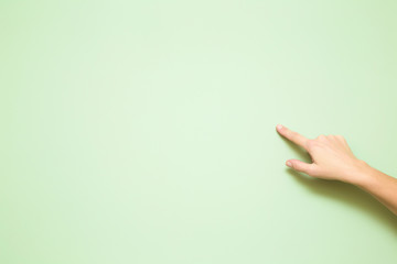 Woman's hand pointing on the light green wall. Mock up for special offers as advertising or other...