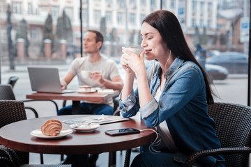 Now and here. Positive delighted girl keeping eyes closed while feeling happiness and listening music