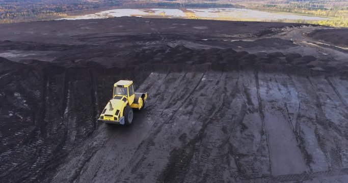 Aerial view of the top of the hill. Industrial area. Yellow dozer at work.