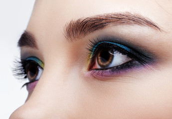 Naklejka premium Closeup macro shot of human female eye. Girl with perfect skin and lilac - blue - yellow eyes shadows