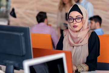 Attractive Muslim young woman working in office on computer