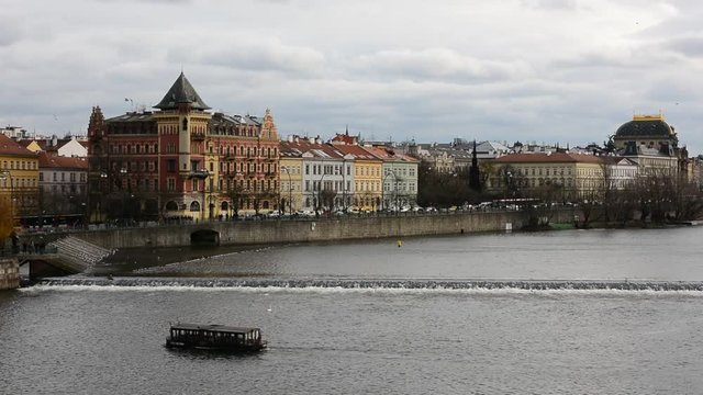 View of a Vltava river with cruising tourist ships and flying birds in Prague city centre.