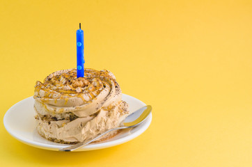 Chocolate cake with cream and a single candle on a yellow background.