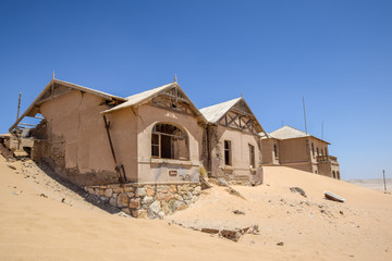 Outside view of one of the abandoned houses in the ghost town of Kolmanskop near Lüderitz in Namibia, Africa. After the diamond rush ended, the houses are slowly getting swallowed by sand and dunes.