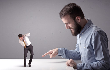 Young businessman fighting with miniature businessman