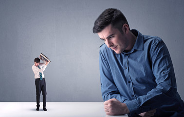 Young businessman fighting with miniature businessman