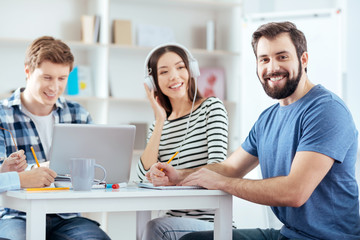 Fototapeta premium Deadline coming. Merry glad colleagues writing down thoughts while laughing and sitting at the table