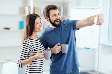  Selfie for lovers. Appealing positive successful couple taking selfie while smiling  and have lunch