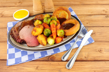 Traditional English roast beef meal with roasted potatoes, vegetables and Yorkshire puddings