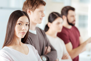 Colleagues backup. Serious ambitious budding woman looking at the camera while becoming part of team and desiring to work