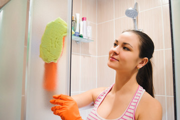 Fototapeta na wymiar portrait of young woman cleaning shower door