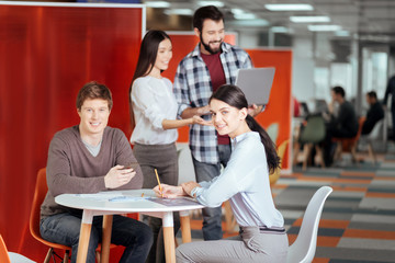 Business deal. Pretty young two colleagues cooperating while  staring at the camera and smiling