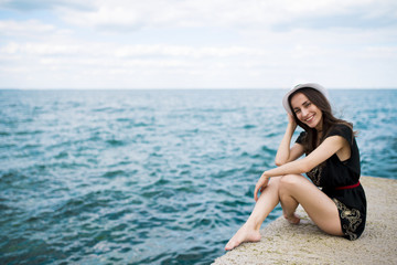 Fototapeta na wymiar Modern beautiful young woman in white hat on the sea beach. Summer rest