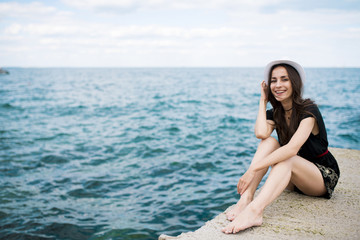 Modern beautiful young woman in white hat on the sea beach. Summer rest