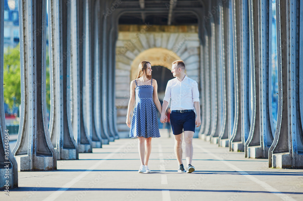 Wall mural couple walking along bir-hakeim bridge in paris, france