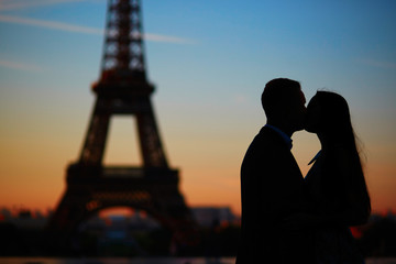 Silhouettes of romantic couple near the Eiffel tower at sunrise