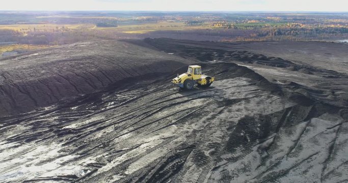 Aerial view of the top of the hill. Industrial area. Yellow dozer at work.