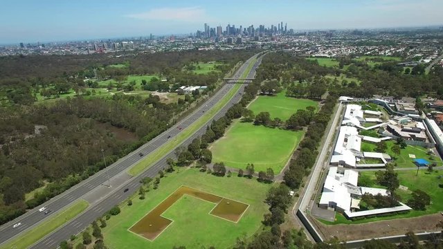 Smooth cinematic aerial flight near highway leading to Melbourne CBD skyline and Melbourne Polytechnic
