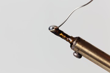 Melting tin on the tip of a soldering iron