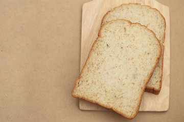 Whole grain breads on wood plate and brown texture background with space for text.