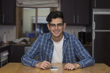 Fototapeta premium young adult with mobile phone in home kitchen