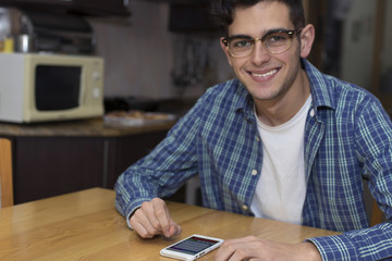 young adult with mobile phone in home kitchen