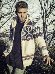 Handsome young man outdoor in winter fashion, wearing black coat and woolen scarf in city park