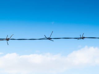 barbed wire with blue sky background with some clouds